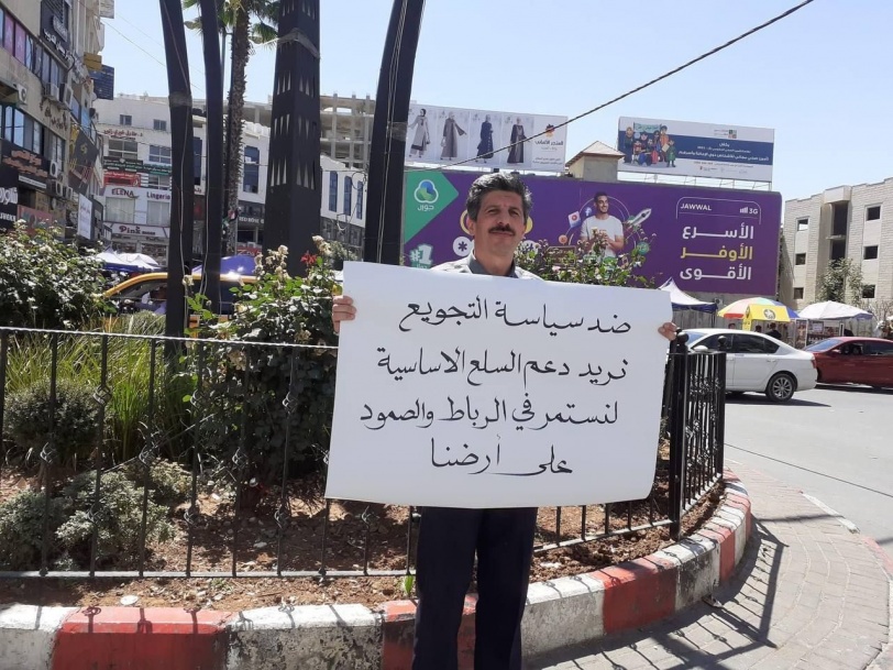 مواطن من مدينة الخليل يرفع لافتة ضد ارتفاع الأسعار