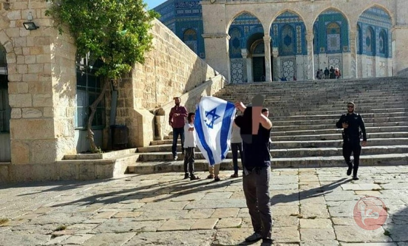 مستوطن يرفع علم إسرائيل خلال اقتحامه الاقصى