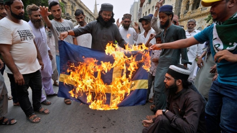 Angry demonstrators in Pakistan burn the Swedish flag in protest against the authorities' permission to burn the Holy Qur'an