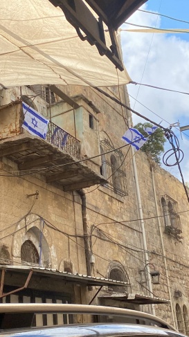 Settlers raise the flag of the occupying state on a building in downtown Hebron