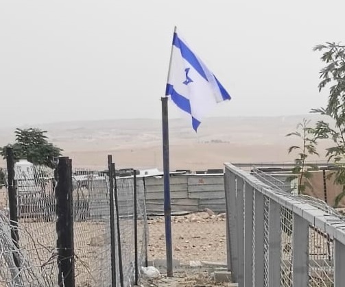 Settlers raise the Israeli flag at the Arab Al-Kaabneh School, west of Jericho