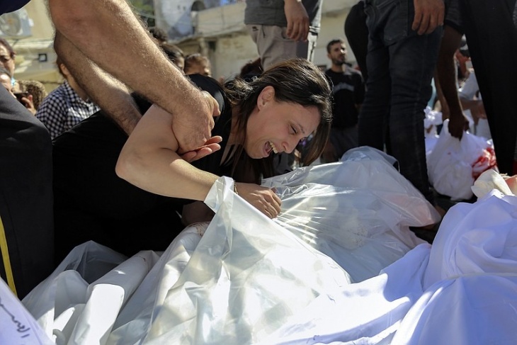 A woman cries over the bodies of her relatives who were martyred in the Israeli air strikes that targeted a Greek Orthodox church in Gaza City on Friday, October 20, 2023.