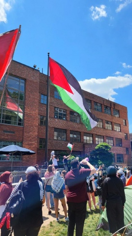 Students raise the Palestinian flag on a tall pole in the middle of George Washington University